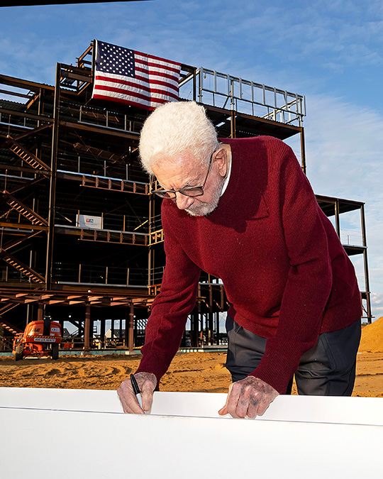 Philanthropist Sheldon Vogel signs the final steel beam