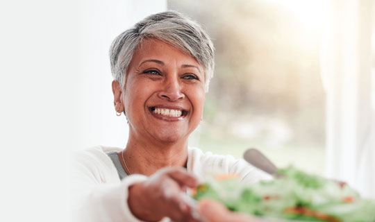 woman passing a bowl of salad to another person