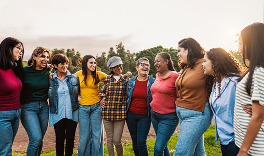 group of diverse women arm in arm in a semi-circle in a park
