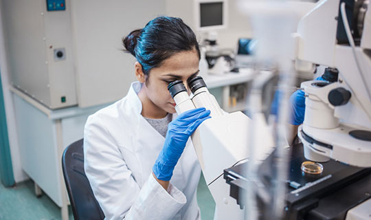 woman researcher looking into a microscope