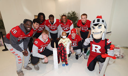 Rutgers football players visiting a patient at Children's Hospital of NJ