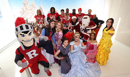 Rutgers football players and a cast of princesses including, Cinderella, Rapunzel, Milan, Belle, and Rey from Star Wars visiting NBI