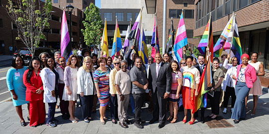 group of NBI Leadership and Staff holding pride flags outside in front of the hospital