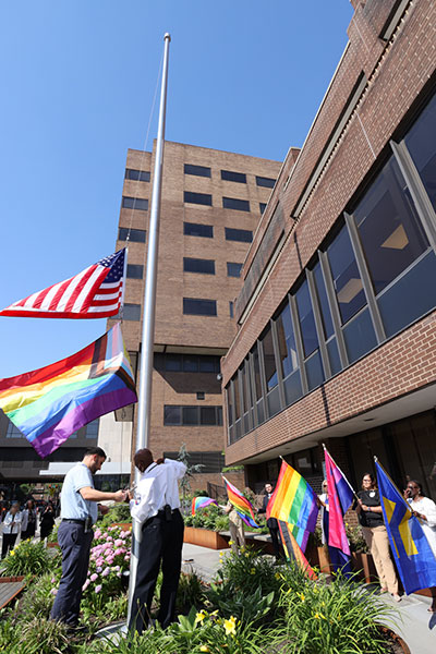 NBI staff raising the pride flag on the flagpole in front of the hospital