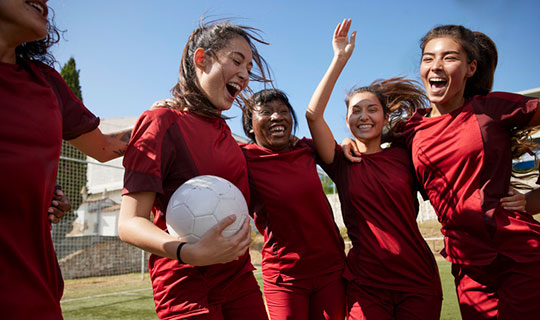 teen girls smiling in a soccer huddle