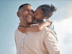 father with daughter on his shoulders, blue sky behind them